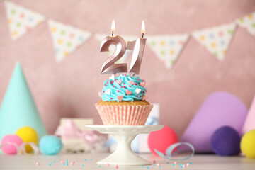 21th birthday. Delicious cupcake with number shaped candles for coming of age party on white table