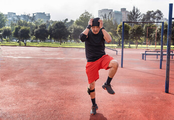 An athletic latin man running in place warming up for exercise in sportswear outdoors