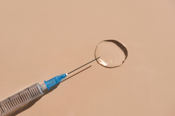 Medical syringe and transparent liquid on a beige background. Flat lay, place for text.