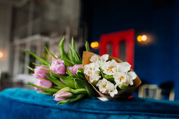 selective focus bouquets of multicolored tulips with green stems. purple and white flowers. in the cozy atmosphere of a dark apartment. spring mood, floral content