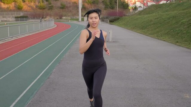 Fit athletic woman running towards camera tracking gimbal shot 