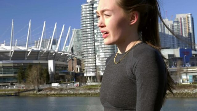 Woman running in city stops to take break stretch arms 