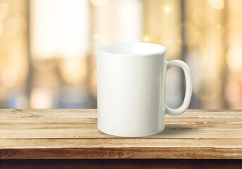 White mug on a wooden background with bright lights in the background. New Year and Christmas.