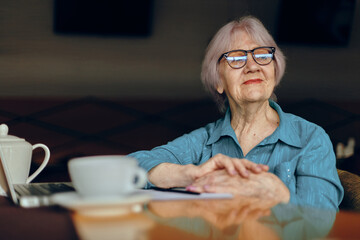 A businesswoman with glasses sits at a table in front of a laptop Freelancer works unaltered