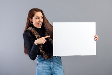 emotional young teenager woman showing blank signboard with copy space, isolated on gray