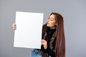 Fototapeta na wymiar smiling young teenager woman showing blank signboard with copy space, isolated on gray
