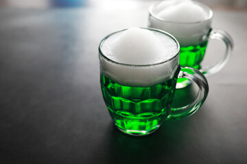 Saint Patrick's Day holiday. National Irish holiday. Green beer. Hand with a mug of emerald beer in a bar.