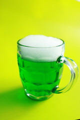 Saint Patrick's Day holiday. National Irish holiday. Green beer. Hand with a mug of emerald beer in a bar.