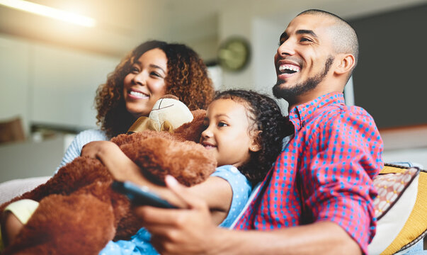 Its Not Movie Night Without The Fam. Shot Of A Happy Young Family Of Three Watching Tv From The Sofa At Home.