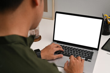 Over shoulder view young man using computer laptop on white table.
