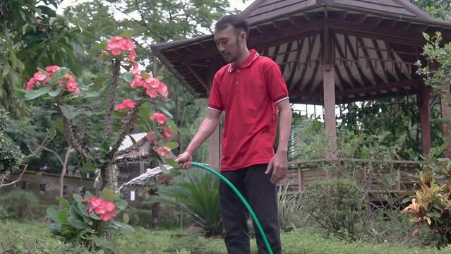 man watering the garden at his house backyard