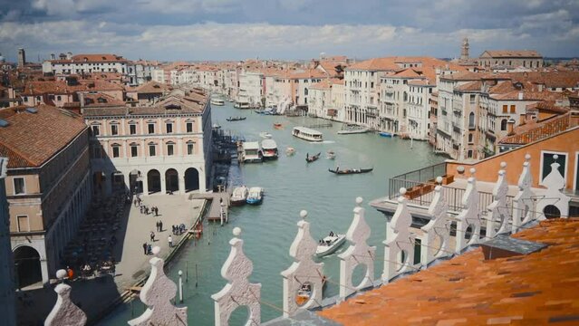 Several gondolas and other sailing boats cruise downtown Venice on a cloudy day. Wide panoramic shot