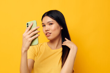 Charming young Asian woman with a phone in her hands makes a selfie studio model unaltered