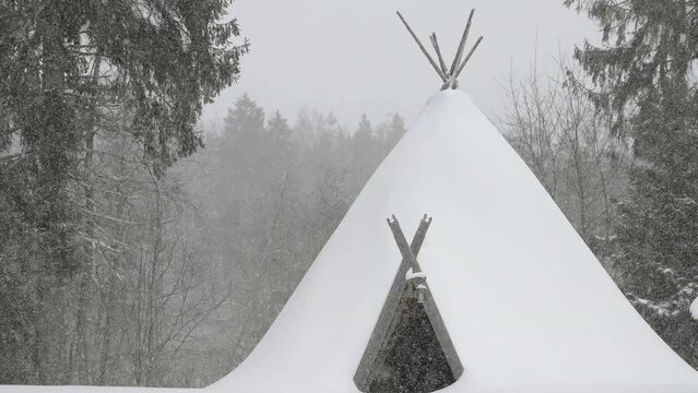 The teepee house in the forest ground covered with snow during the heavy snowfall in Estonia