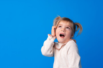 Funny portrait of a cute little blonde girl pretend talking on the phone