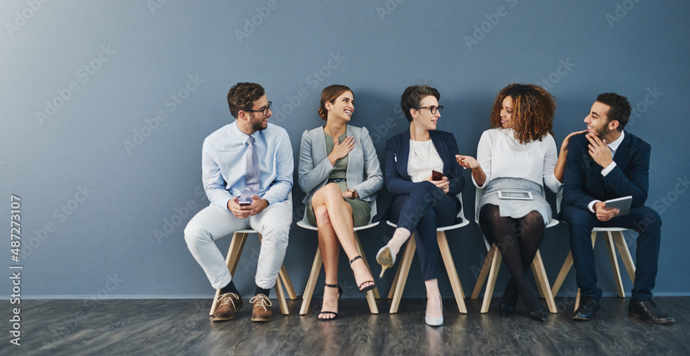 Poster Friendly conversation calms the pre-interview nerves. Studio shot of a group of businesspeople talking while waiting in line against a gray background.