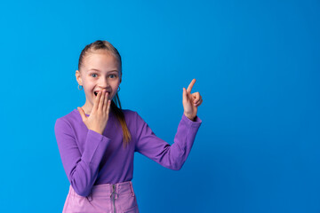 Little girl pointing at copy space against blue background