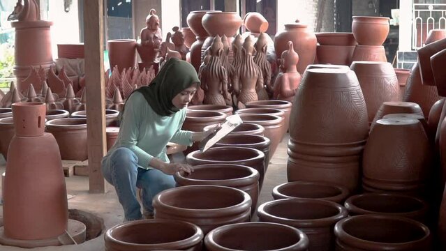 veiled businesswoman looking at pottery while using a pad