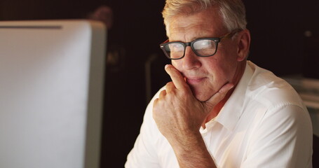Staying determined in his pursuit of success. 4k video of a mature businessman working late on a computer in an office.