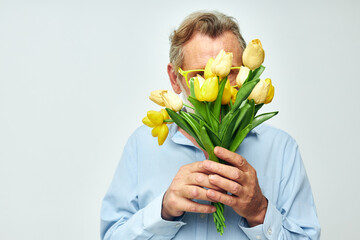 old man in a blue shirt with a bouquet of flowers light background