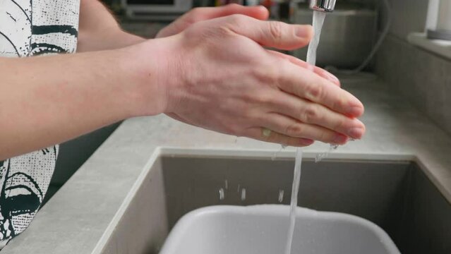 A man washing his hands at the kitchen sink.