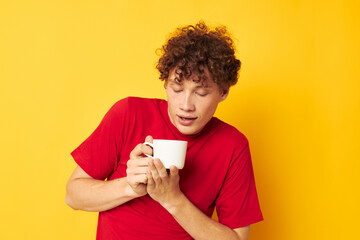 Young curly-haired man white mug in the hands of a drink isolated background unaltered