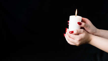 Crop person with burning candle. Crop anonymous person demonstrating white candle black background