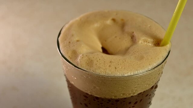 adding ice cubes to iced coffee closeup