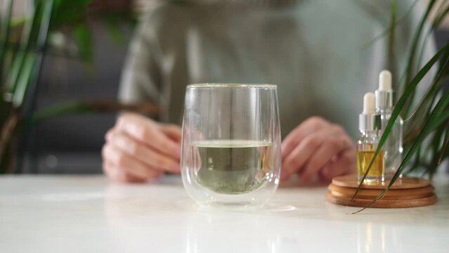 Woman hand holding dropper with green chlorophyll at home. Immunity booster concept 