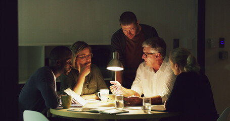 The only way to get ahead is together. 4k video of a group of businesspeople working late in an office.