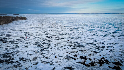 The point of land reaches the frozen lake with blue sky