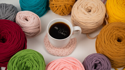Fototapeta na wymiar Close-up of multicolored cotton skeins and a mug of black coffee