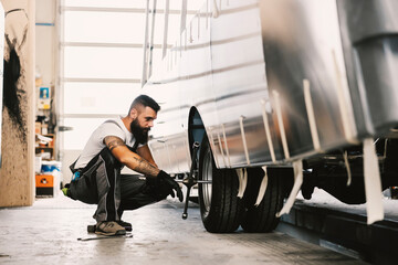 An auto-mechanic changing tire on a vehicle at workshop.