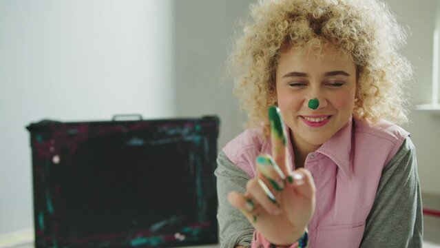 Happy Female Artist Putting Colors On Her nose Using Finger