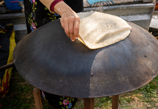 Arabian female person prepare flatbread (other names is pita, lavash, lafa, roti, chapati) on hot saj