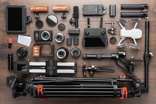 Different video making equipment for indie cinema production. Video production tools on brown wooden table view from above. Short movie production essentials.