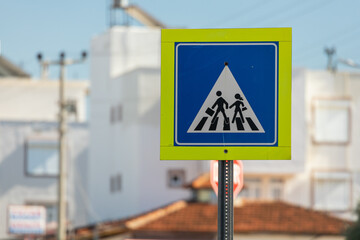 pedestrian crossing road sign next to the school on the background of the city