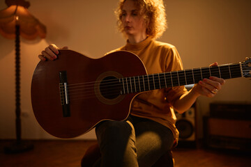 Obraz premium Woman playing acoustic guitar in a retro vintage room.