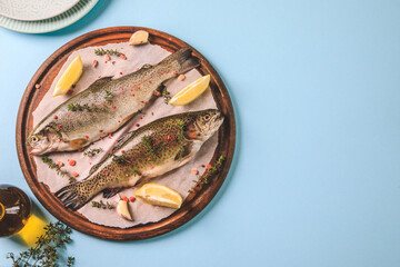 two raw rainbow trouts on paper with thyme and lemon. Fish trout. Top view. Free space for your text.