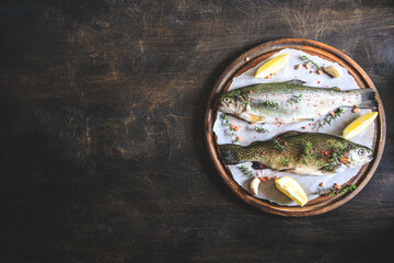 two raw rainbow trouts on paper with thyme and lemon. Fish trout. Top view. Free space for your text.