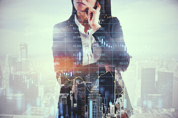 Attractive thoughtful european businesswoman standing on bright city background with candlestick forex grid chart. Trade, finance and economy concept. Double exposure.