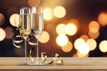 Glasses and bottle of champagne with serpentine streamers against lights on background.