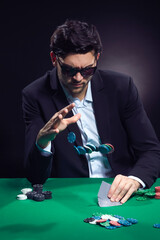 Gaming Concepts. Emotional Handsome Caucasian Brunet Pocker Player At Pocker Table With Chips and Cards While Throwing Chips and Drinking Alcohol.