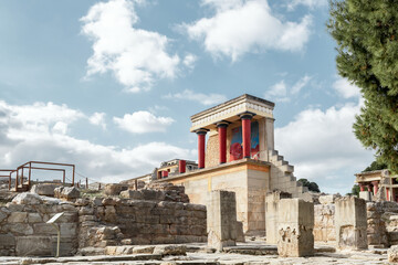 Minoan palace Knossos at Heraklion, Crete island, Greece. North Entrance with charging bull fresco and three red columns against a dramatic cloudy sky