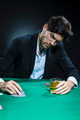 Concentrated Handsome Caucasian Brunet  Pocker Player At Pocker Table With Chips While Drinking Alcohol While Playing.