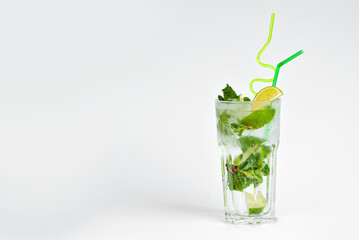 Green cocktail on a white background. Alcoholic mojito with ice close up. Lime, mint and straw in a cocktail. Copy space and wine place for text near the glass.