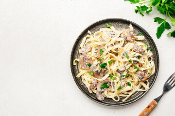 Mushroom Tagliatelle Pasta with parmesan cheese and cream sauce on white background, top view. Prepared italian pasta with champignon on gray plate