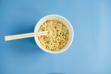 instant noodles with wooden chopsticks on a blue background, top view. Korean national dish.