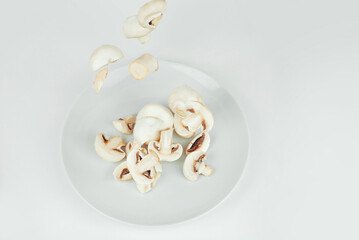 Mushrooms on a white background close up. Mushrooms fly in the air. Food falls into a white plate....
