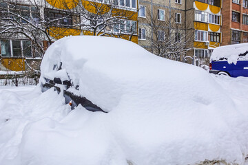 The car is covered in snow. Winter in Russia